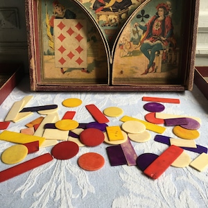 May include: A vintage wooden game with various coloured geometric shapes. The game box displays illustrations of playing cards and figures. The shapes are red, yellow, purple, and off-white.