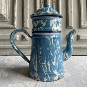 Könnte beinhalten: Vintage Kaffeekanne aus blau-weißem Emaille mit Deckel. Die Kanne hat ein klassisches Design mit Griff und Ausguss. Das blau-weiße Muster verleiht ihr eine rustikale, ländliche Ästhetik. Eine charmante Ergänzung für jede Küche.