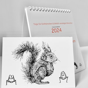 Der Kalender Yoga für Eichhörnchen & ähnlich veranlagte Menschen, Postkartenkalender 2024 steht aufgeklappt auf einer weißen Fläche.Im Vordergrund eine abgetrennte Postkarte.
