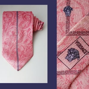 Puede incluir: Corbata de seda rosa con un diseño estampado en blanco y negro con un borde de clave griega y un logotipo de Versace con una cabeza de Medusa.