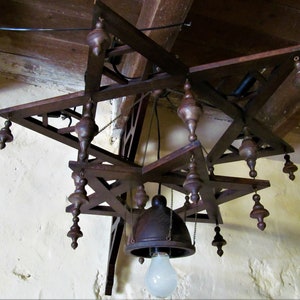 May include: A wooden chandelier with a star-shaped design and multiple hanging bulbs. The chandelier is made of dark brown wood and has a rustic look.