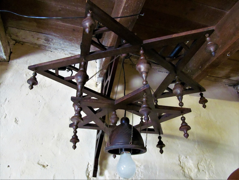 May include: A wooden chandelier with a star-shaped design and multiple hanging bulbs. The chandelier is made of dark brown wood and has a rustic look.