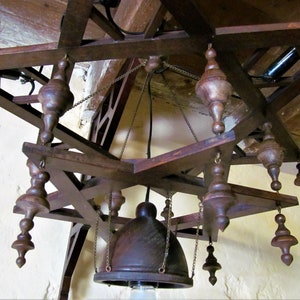 May include: A wooden star-shaped chandelier with a dark brown finish. The chandelier has multiple hanging bulbs and a central dome-shaped light fixture.
