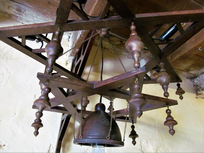 May include: A wooden star-shaped chandelier with a dark brown finish. The chandelier has multiple hanging bulbs and a central dome-shaped light fixture.