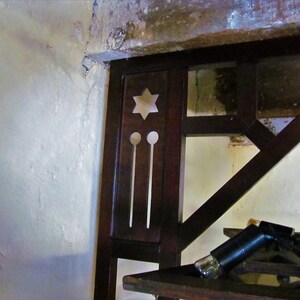 May include: Close-up of a dark wood shelf unit with a star-shaped cutout and two round cutouts. The shelf unit is attached to a white wall.