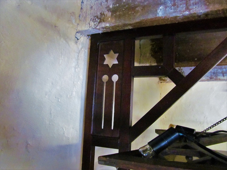 May include: Close-up of a dark wood shelf unit with a star-shaped cutout and two round cutouts. The shelf unit is attached to a white wall.