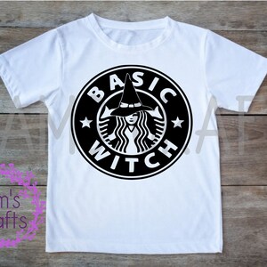 May include: White t-shirt featuring a black and white graphic of a witch wearing a hat, with the text "BASIC WITCH" in a circle.