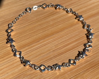 May include: A silver necklace with a chain and alternating star and diamond-shaped charms.