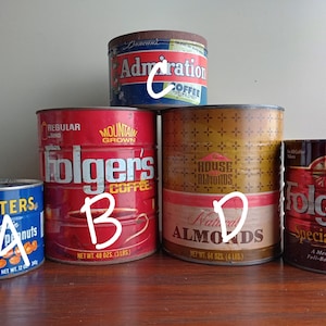 May include: An assortment of vintage food cans, including Planters peanuts, Folgers coffee, House Almonds, and Admiration coffee. The cans are various sizes and colors, with labels featuring text and graphics. The Folgers coffee can is 48 oz (3 lbs).