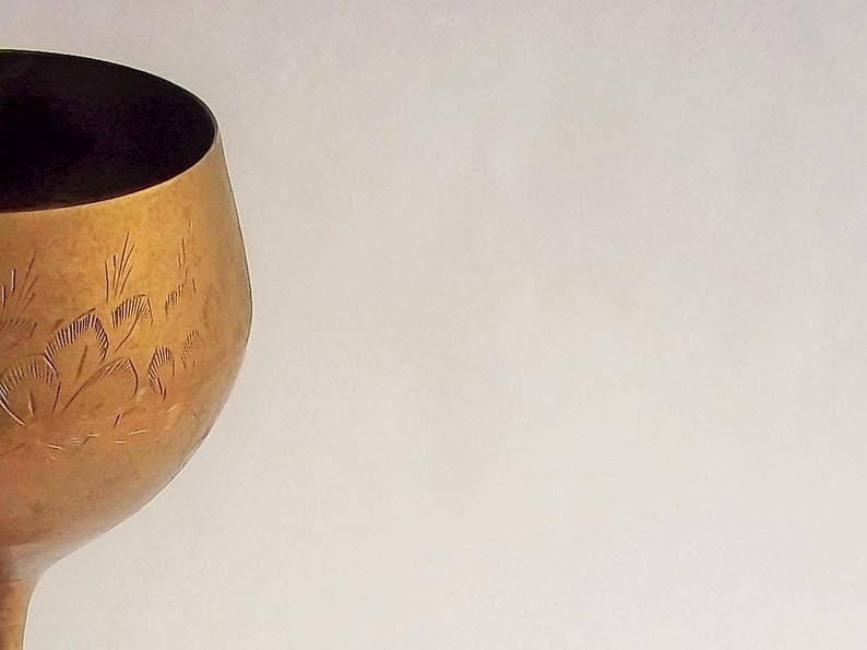 A 12" tall brass goblet.
This is a vintage brass goblet with a leaf etched design around the bowl and the base. 
The bottom of the goblet bowl is not smooth and the bottom goes into the stem a little bit so it's not recommended to drink out of it. 
Great for many styles of décor such as bohemian, farmhouse, romantic or cottage.  
approx. 
12" Tall
4 1/2-3/4" at widest point
3 3/4" opening
4 1/2" depth
base is 4 3/4" diameter
3/8" width at middle of stem
India is etched on bottom