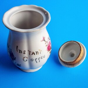 A lovely vintage Lipper & Mann coffee container with lid. It has Instant Coffee in gold letters on front. This coffee canister has a pompadour rose design which would be great for a French Country Cottage décor kitchen. Lid with rose pattern and gold trim. 6 1/2" High 3 1/2" Wide 5" Depth the lid fits nicely, (has cork around base of lid to seal when closed), Sold as Found; will need to be cleaned; has a few areas where discoloration are like specks and could have occurred during creation
