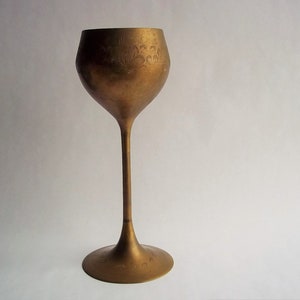 A 12" tall brass goblet.
This is a vintage brass goblet with a leaf etched design around the bowl and the base. 
The bottom of the goblet bowl is not smooth and the bottom goes into the stem a little bit so it's not recommended to drink out of it. 
Great for many styles of décor such as bohemian, farmhouse, romantic or cottage.  
approx. 
12" Tall
4 1/2-3/4" at widest point
3 3/4" opening
4 1/2" depth
base is 4 3/4" diameter
3/8" width at middle of stem
India is etched on bottom