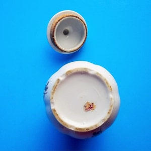 A lovely vintage Lipper & Mann coffee container with lid. It has Instant Coffee in gold letters on front. This coffee canister has a pompadour rose design which would be great for a French Country Cottage décor kitchen. Lid with rose pattern and gold trim. 6 1/2" High 3 1/2" Wide 5" Depth the lid fits nicely, (has cork around base of lid to seal when closed), Sold as Found; will need to be cleaned; has a few areas where discoloration are like specks and could have occurred during creation