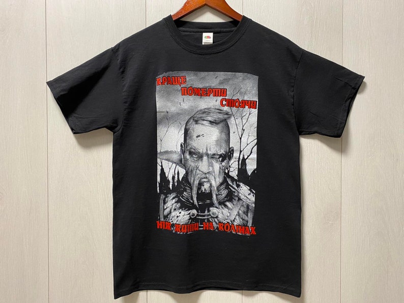 Może przedstawiać: Czarny T-shirt z nadrukiem graficznym przedstawiającym mężczyznę z brodą i wąsami. Tekst na koszulce brzmi "KPAИHE ПOMEPTИ СЛОЖHA НИК-РОДИ-НА-РОДИНА".