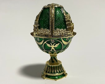 May include: A decorative green and gold egg-shaped trinket box with a detailed architectural design. The egg features a hinged top, ornate gold accents, and is set on a pedestal base. The egg is approximately 4 inches tall.