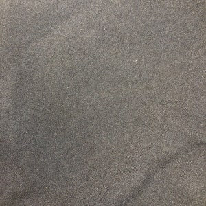 Op de afbeelding: Close-up van een donkergrijze stof met een subtiele geweven textuur.