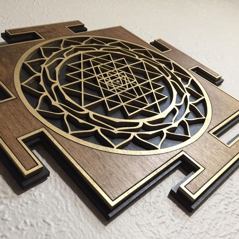 May include: A wooden wall art piece featuring a layered design. The artwork showcases a central geometric pattern in gold, set against a dark background, and framed by a brown wooden border. The piece has a three-dimensional effect.