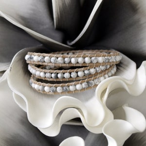 May include: A triple wrap bracelet with white and gray marble beads and brown leather cord.