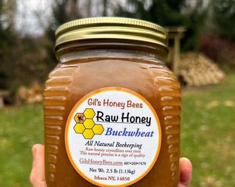 May include: A jar of Gil's Honey Bees raw buckwheat honey. The label features a bee graphic and text that reads "All Natural Beekeeping." The jar contains 2.5 lb (1.13kg) of honey and is sealed with a gold lid.