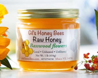 May include: A glass jar of raw honey labeled "Gil's Honey Bees Raw Honey Basswood Flowers". The label also includes the text "Local Unheated Unfiltered Net Wt. 1 lb (454g) Gil's HoneyBees.com 607-275-6740 Ithaca NY, 14850".