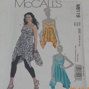 May include: A sewing pattern for a sleeveless dress with a halter neckline. The pattern is for sizes 4-6-8-10-12. The pattern is called McCall's M6119 AX5. The pattern includes three different styles of dresses. The first style is a black and white patterned dress with a long, flowing skirt. The second style is a yellow and orange patterned dress with a shorter skirt. The third style is a blue and white patterned dress with a shorter skirt.