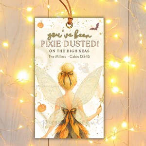 Könnte beinhalten: Ein rechteckiges Geschenkanhänger mit braunem Lederband und einer Feen-Illustration mit blondem Haar und Flügeln. Der Text lautet you've been PIXIE DUSTED! ON THE HIGH SEAS, The Millers, Cabin 12345, und ALL TEXT IS EDITABLE except you've been.