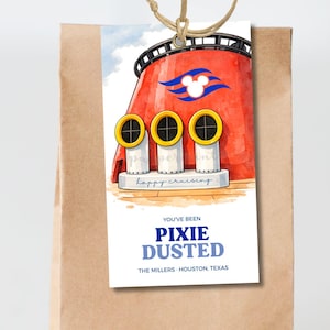 以下が含まれることがあります： 赤いクルーズ船の煙突のイラストと青い文字で「YOU'VE BEEN PIXIE DUSTED」と書かれたギフトタグ。タグは茶色の紙袋に紐で取り付けられています。