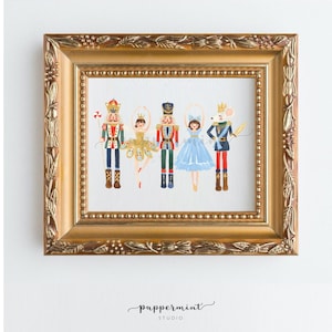 May include: A framed illustration of a Nutcracker, a ballerina, and a mouse king. The Nutcracker is wearing a red and gold uniform, the ballerina is wearing a gold and white tutu, and the mouse king is wearing a blue and gold uniform. The illustration is set against a white background.