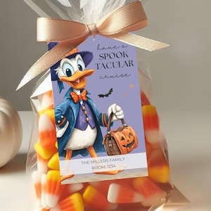 May include: A clear plastic bag filled with orange, yellow, and white candy corn, tied with a tan ribbon. A rectangular tag features a cartoon duck in a blue suit holding a pumpkin bucket, with the text have a SPOOK TACULAR cruise, THE MILLERS FAMILY, and ROOM: 1234.