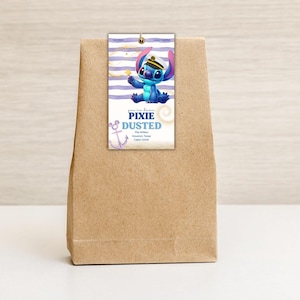 May include: A brown paper bag with a tag featuring a blue cartoon character wearing a sailor hat. The tag has the words "Pixie Dusted" and an anchor graphic. The background of the tag has white and purple stripes.