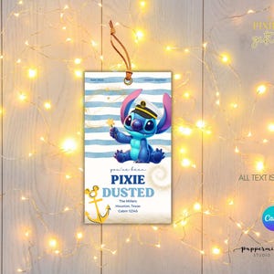May include: A rectangular gift tag featuring a blue cartoon character in a sailor hat holding a star. The tag has blue and white stripes, the words "PIXIE DUSTED", and editable text. A brown string is attached to the top.