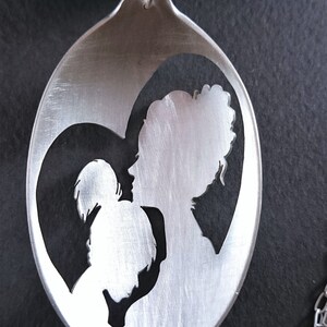 Pu&ograve; includere: Un cucchiaio d'argento con un design a forma di cuore, ritagliato a forma di madre e figlio.