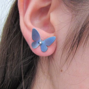 May include: A pair of blue butterfly earrings with a silver bead in the center.