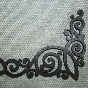 May include: Black wooden corner design with intricate scrollwork and cutouts. The design is reminiscent of a traditional Victorian style.