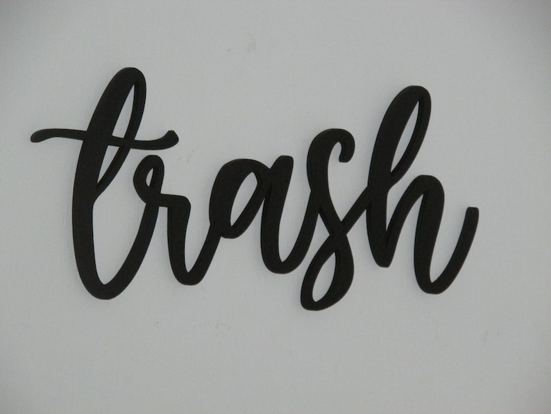 May include: Black cursive word "trash" cut out of wood.