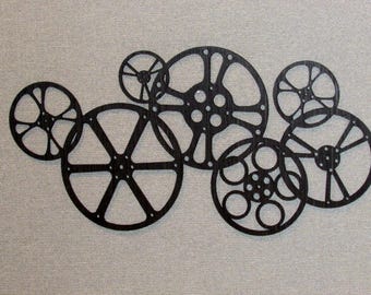 May include: A wall decor made of black metal film reels of different sizes. The reels are arranged in a cluster, creating a unique and modern design.