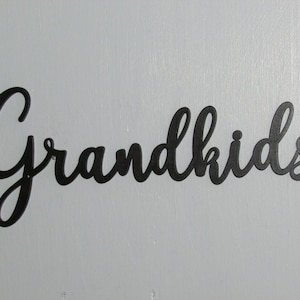 May include: Black metal wall decor with the word "Grandkids" written in a cursive font.