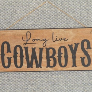 May include: A wooden sign with the text "Long live cowboys" in black lettering on a brown background.