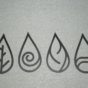 May include: Four black metal teardrop-shaped wall decor pieces with different designs inside each teardrop. The designs are a branch, a spiral, a wavy line, and a curved line.