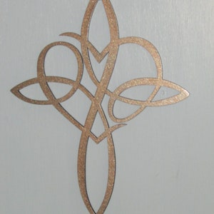 May include: A gold-colored metal Celtic knot cross with a heart shape in the center. The cross is intricately designed with a knot pattern.