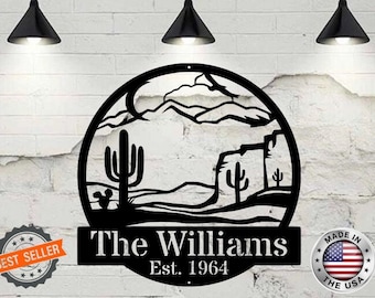 May include: Black metal sign with a desert landscape silhouette, including mountains, cacti, and a sunset. The sign reads "The Williams Est. 1964" and has a "Made in the USA" label.