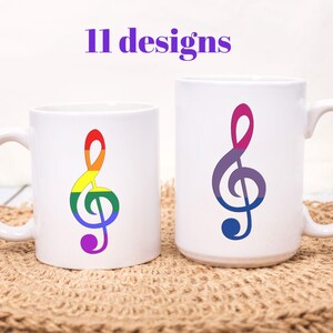 May include: Two white ceramic mugs with musical note designs in rainbow and purple-blue gradients. The text "11 designs" is above the mugs. The mugs are on a woven mat.