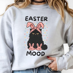 May include: A white ceramic mug with a black handle and the text "But First, Coffee" in a bold, black font. The mug is set against a blurred background, suggesting a cozy setting.