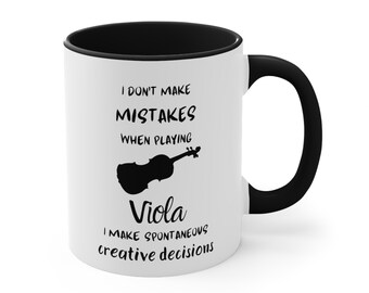 May include: White coffee mug with a black rim and handle. The mug has a black silhouette of a viola and text that reads "I don't make mistakes when playing viola I make spontaneous creative decisions."