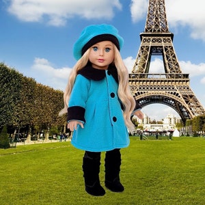 May include: A blue fleece coat with a black collar and cuffs, worn by a doll with blonde hair and a blue beret. The doll is standing in front of the Eiffel Tower.