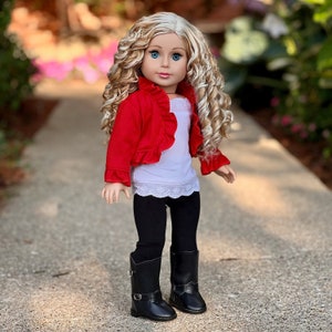 May include: A doll wearing a red ruffled cardigan, a white tank top with lace trim, black leggings, and black boots. The doll has blonde curly hair and blue eyes.