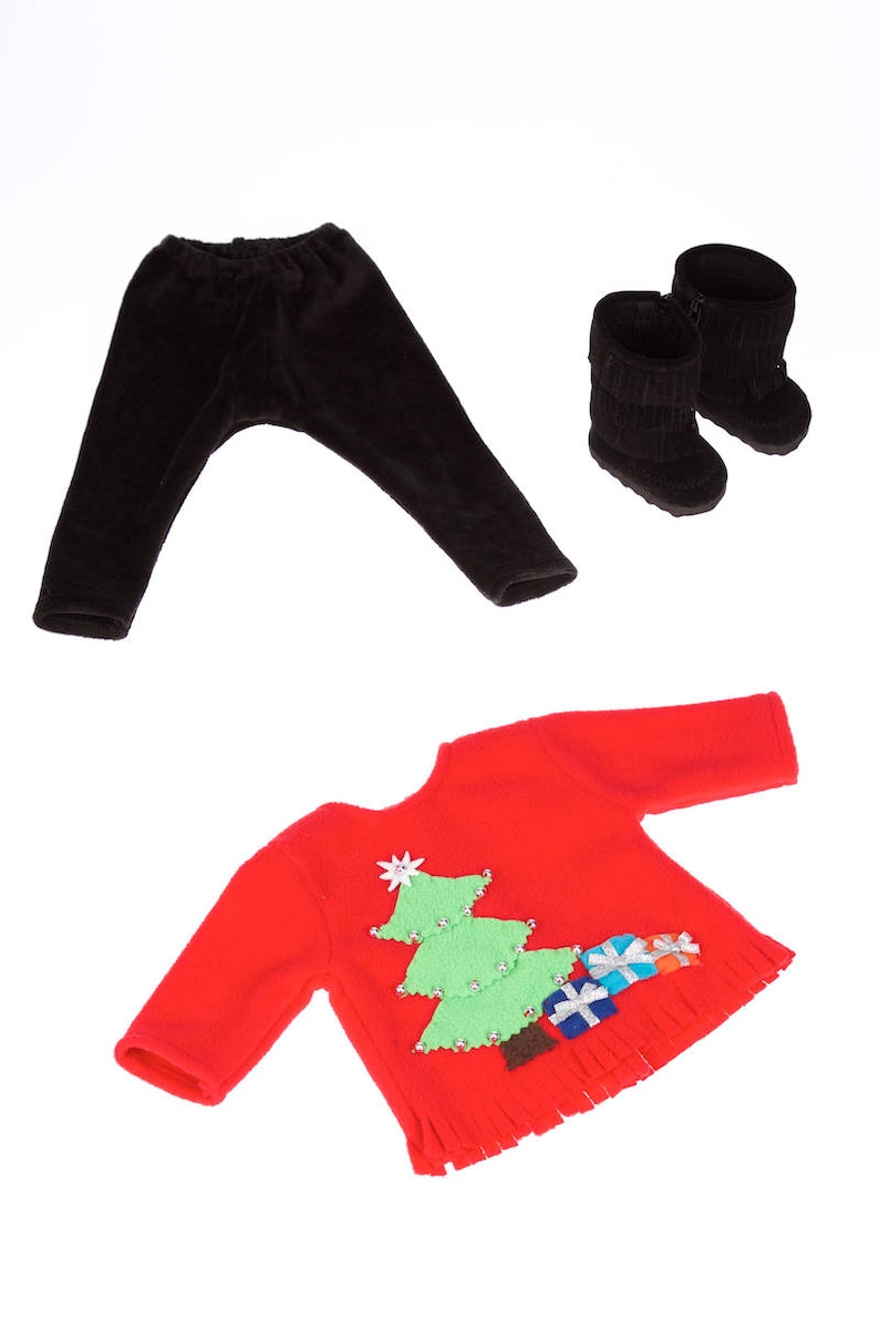May include: A red Christmas sweater with a green Christmas tree and presents on the front. The sweater has a fringe trim. The sweater is paired with black leggings and black boots.