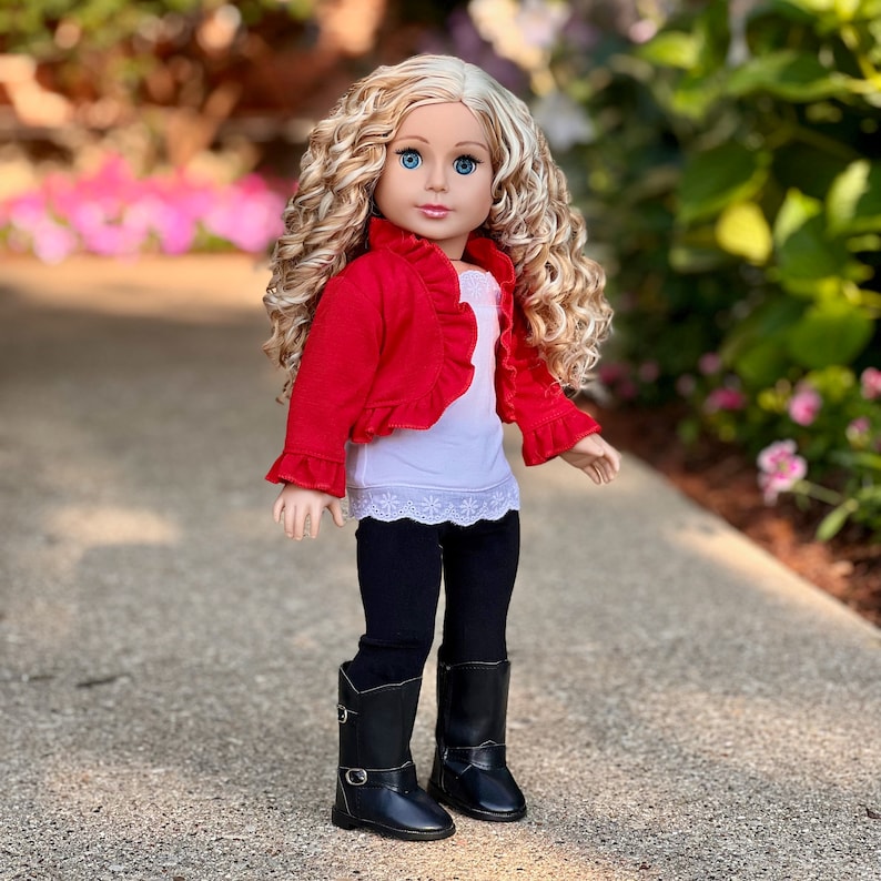 May include: A doll with blonde curly hair wearing a red ruffled jacket, a white lace top, black leggings, and black boots.
