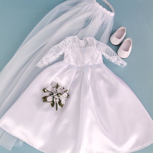 May include: A white satin bridal gown with lace sleeves and a veil. The gown has a bouquet of white flowers and green leaves. The set also includes a pair of white shoes.