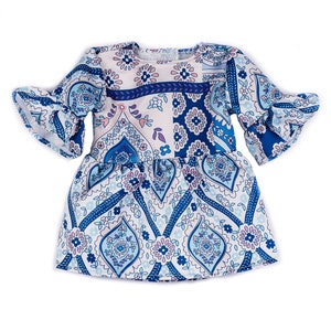 May include: A white and blue patterned dress with a ruffled sleeve. The dress has a paisley design with pink and blue accents.